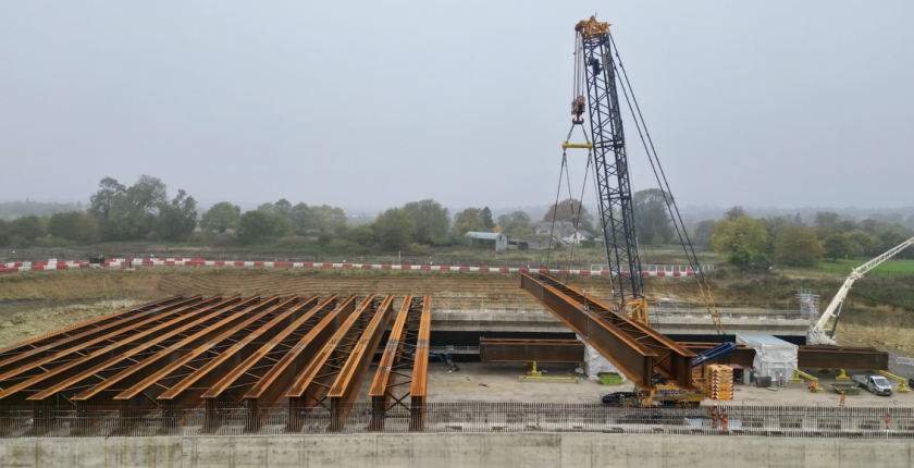 The beams, each weighing up to 105 tonnes, are being lifted into place in pairs. These beams will form the foundation for a concrete deck constructed with pre-cast slabs. Once completed, the deck will support 2,700 cubic metres of earth, forming the final landscaped structure.